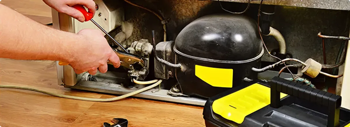 Refrigerator repair technician fixing the compressor and wiring in University Place, WA