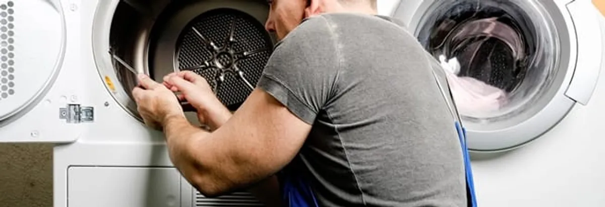 Dryer repair technician fixing a clothes dryer drum in Tacoma, WA