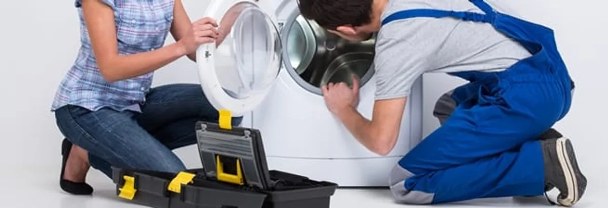 Washer repair technician inspecting a front-load washing machine with tools in Tacoma, WA