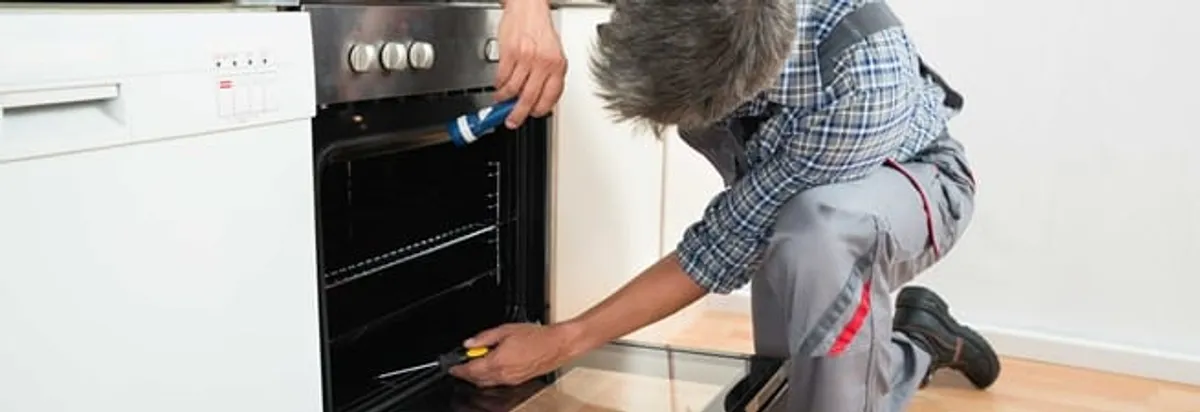 Oven repair technician inspecting and servicing an electric oven in Tacoma, WA