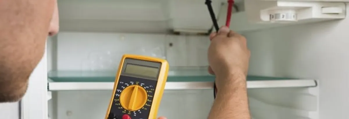 Refrigerator repair technician testing electrical components with a multimeter in Tacoma, WA